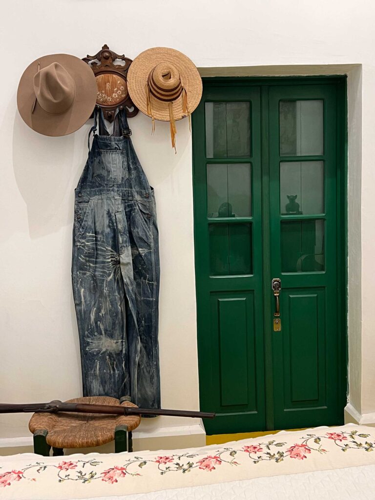 Tina's AI-created image: a green door, next to which are hung hats and a pair of overalls