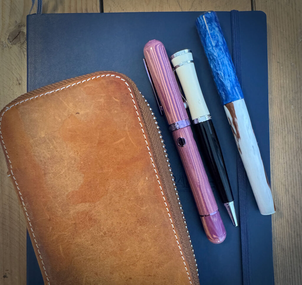 photo of a leather pen case with pens next to it